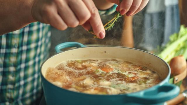 Mujer cocinando en una pota con verduras.