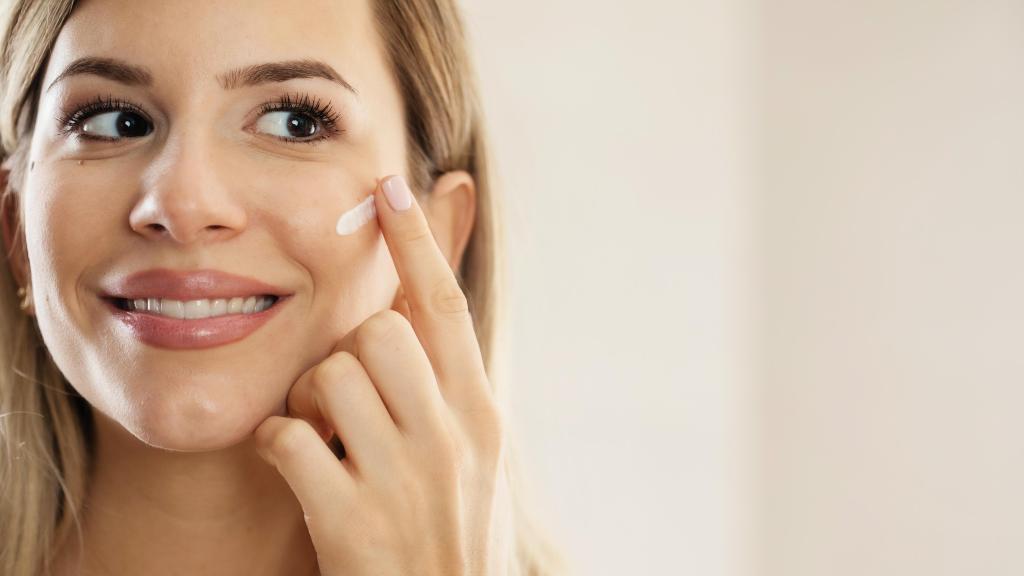 Mujer aplicándose crema en el rostro.