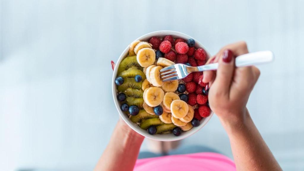 Mujer comiendo un bol de fruta.