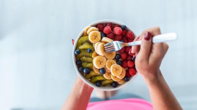 Mujer comiendo un bol de fruta.