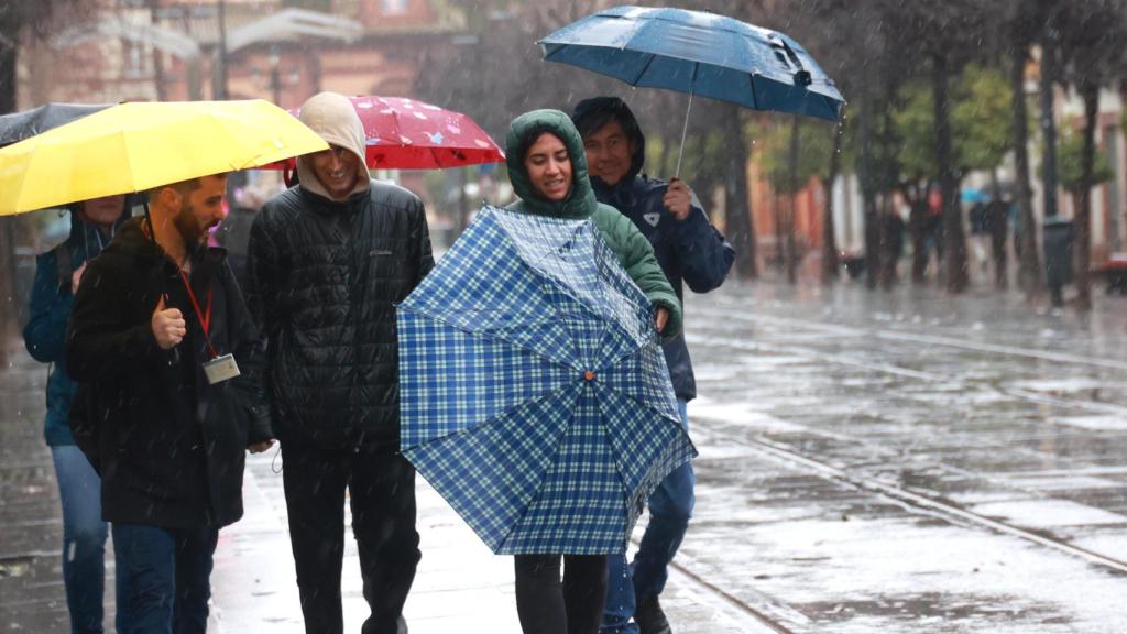 Un grupo de personas se protege de la lluvia en Sevilla.