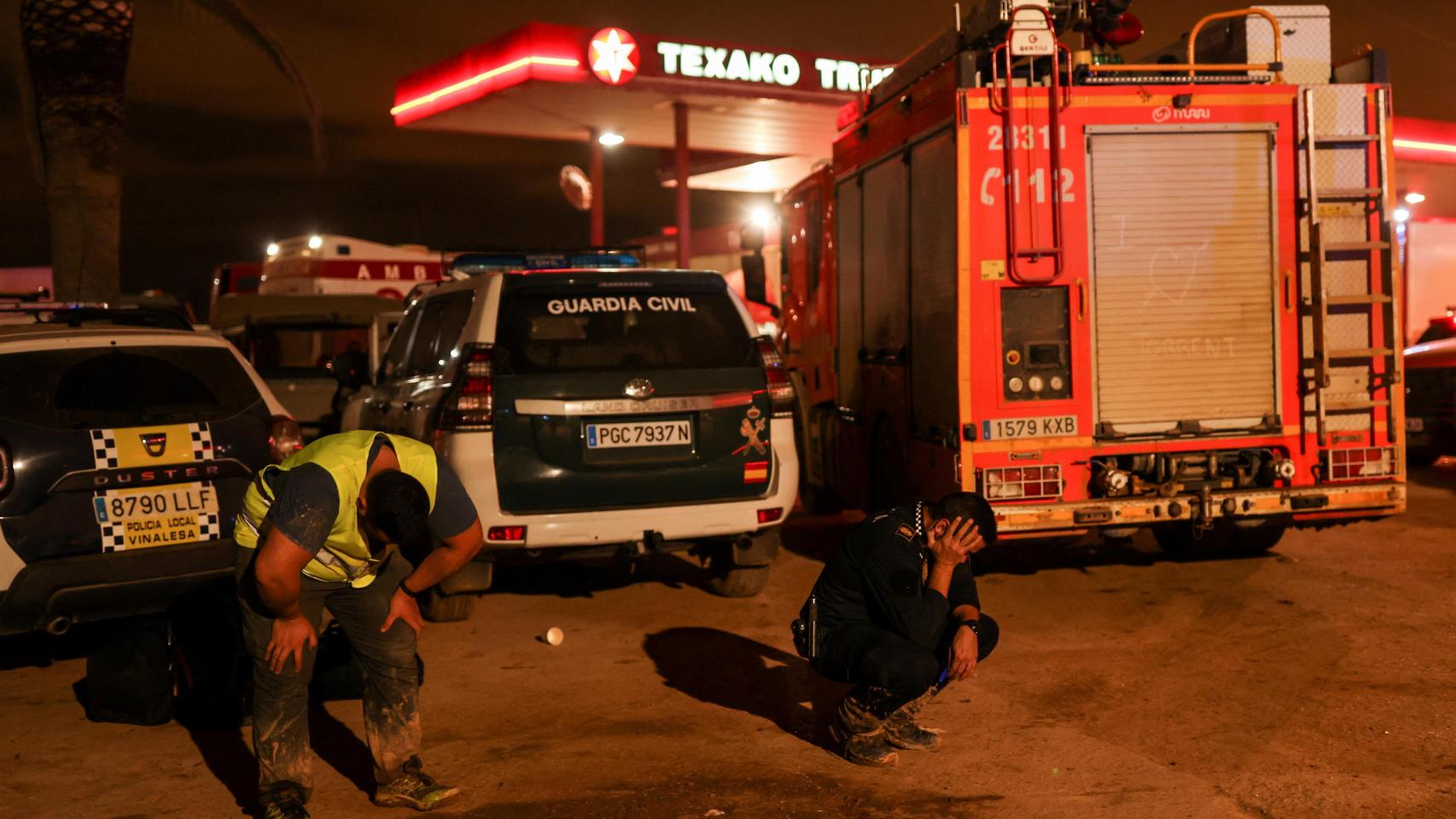 Trabajadores descansan de las labores de rescate y limpieza cerca de una gasolinera en Valencia.