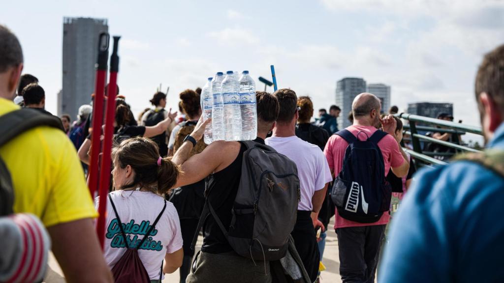 Un joven carga con botellas de agua hacia Paiporta