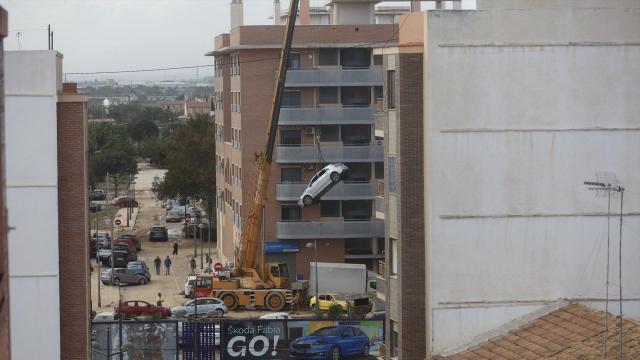 Vista de una grúa retirando coches tras el paso de la DANA en el barrio de la Torre.