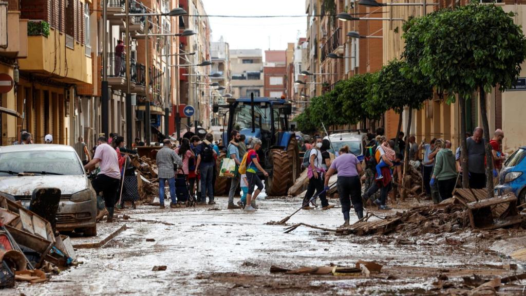 La gente se reúne para limpiar una calle cubierta de barro en Sedavi.