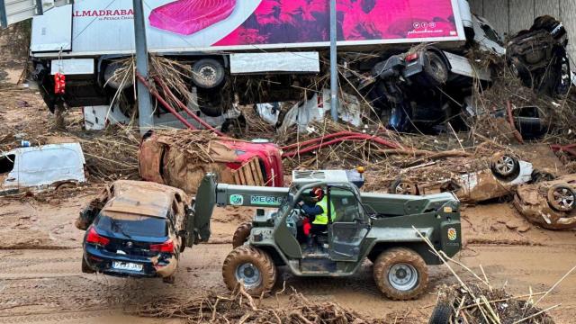 Un vehículo de la UME saca los coches destruidos por la DANA en una carretera de Torrent.