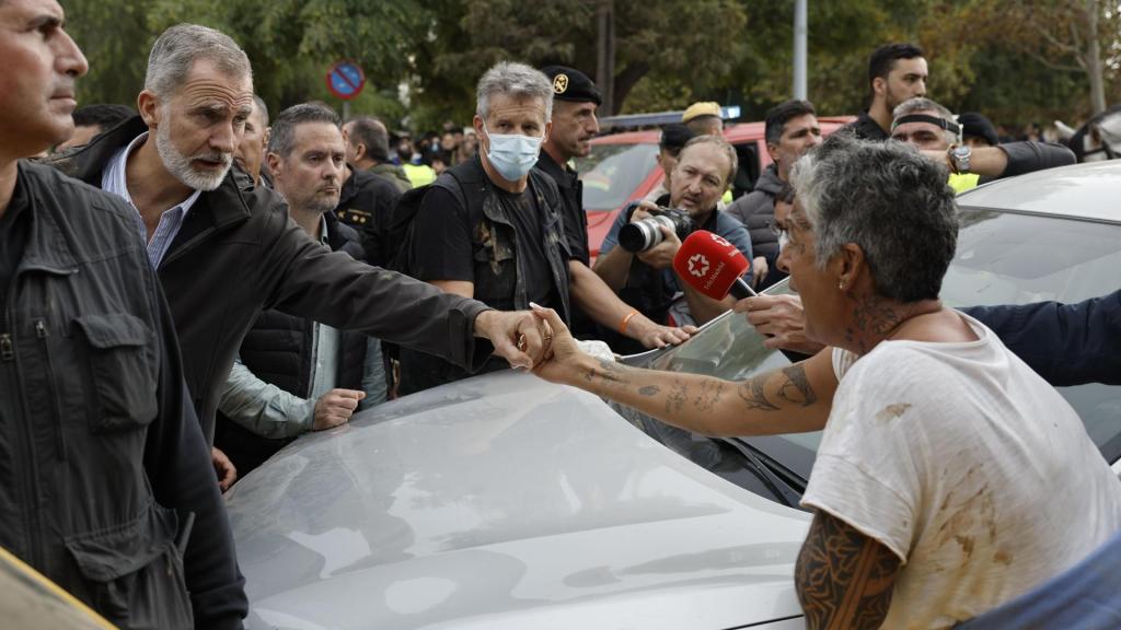 El rey Felipe sostiene la mano de una vecina indignada, durante su visita a Paiporta este domingo