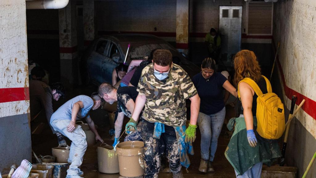 Un grupo de voluntarios tratan de drenar, cubo a cubo, un garaje de Alfafar.