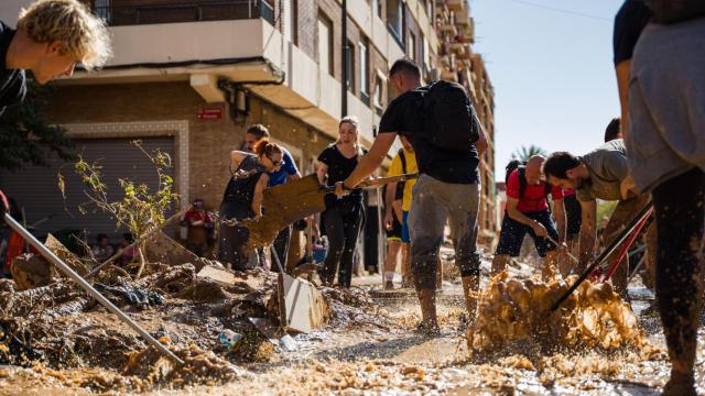 Un grupo de voluntarios tratan de extraer barro de las calles de Paiporta.