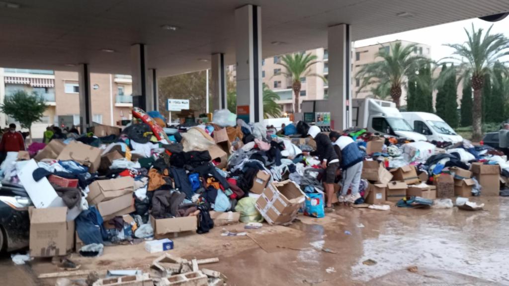 Los voluntarios de la Fundación Ayuda Una Familia, este domingo, repartiendo raciones de comida caliente en la Repsol de Catarroja.