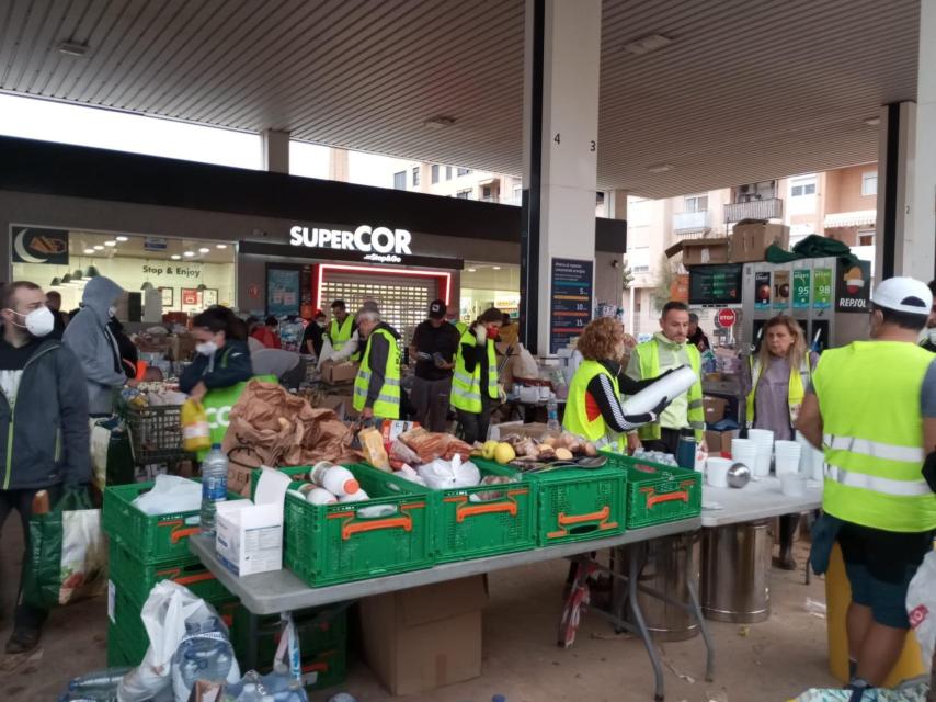 Los voluntarios de la Fundación Ayuda Una Familia, este domingo, repartiendo raciones de comida caliente en la Repsol de Catarroja.