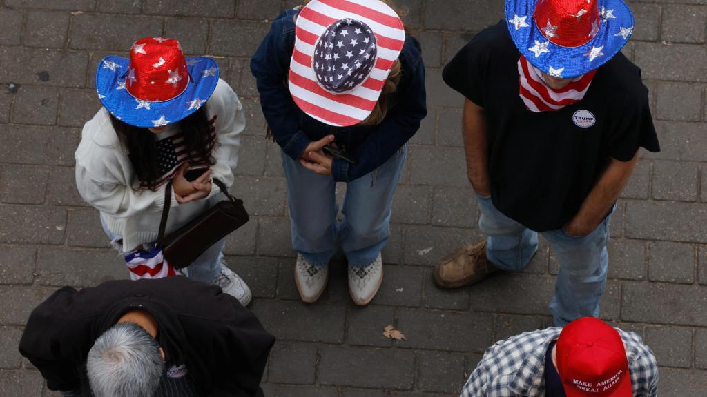 Simpatizantes del Partido Republicano portan sombreros con la bandera estadounidense a la entrada de un mitin de Donald Trump.