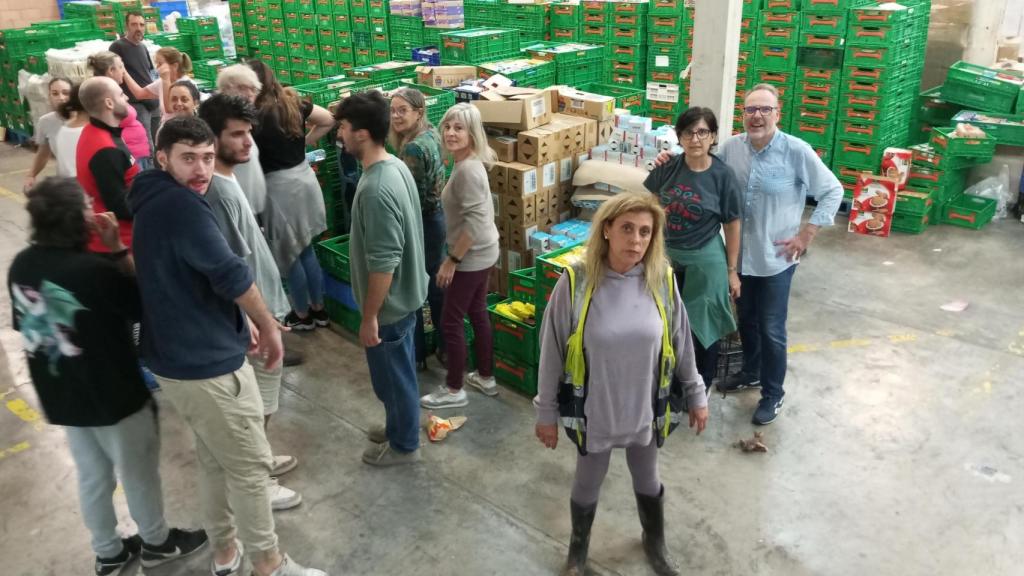 Marise García Llop, coordinadora de la Fundación Ayuda Una Familia (c), este domingo, junto a los voluntarios que estaban clasificando comida en su centro logístico.