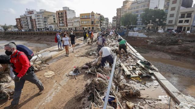 Decenas de voluntarios trabajan para despejar uno de los puentes de Paiporta, Valencia.