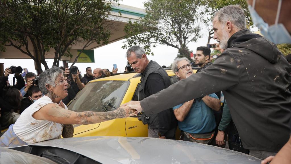 Felipe VI cogiendo la mano de una vecina de Paiporta afectada por la DANA.