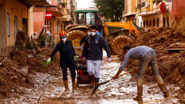 Gente limpiando el barro acumulado en las calles de Massanassa.