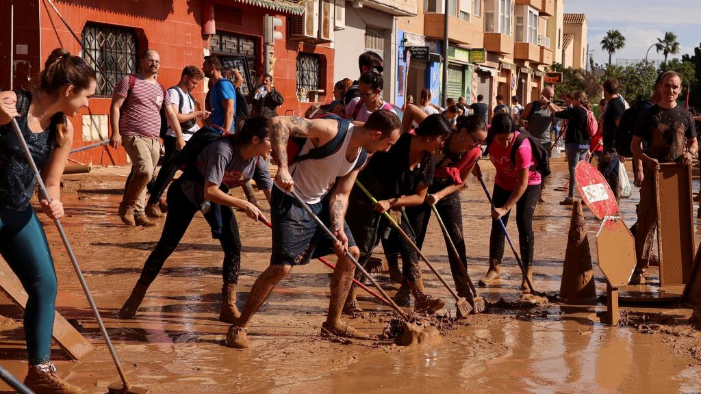 Fotografía de voluntarios y vecinos colaborando por limpiar las calles de los pueblos afectados por la DANA en Valencia.