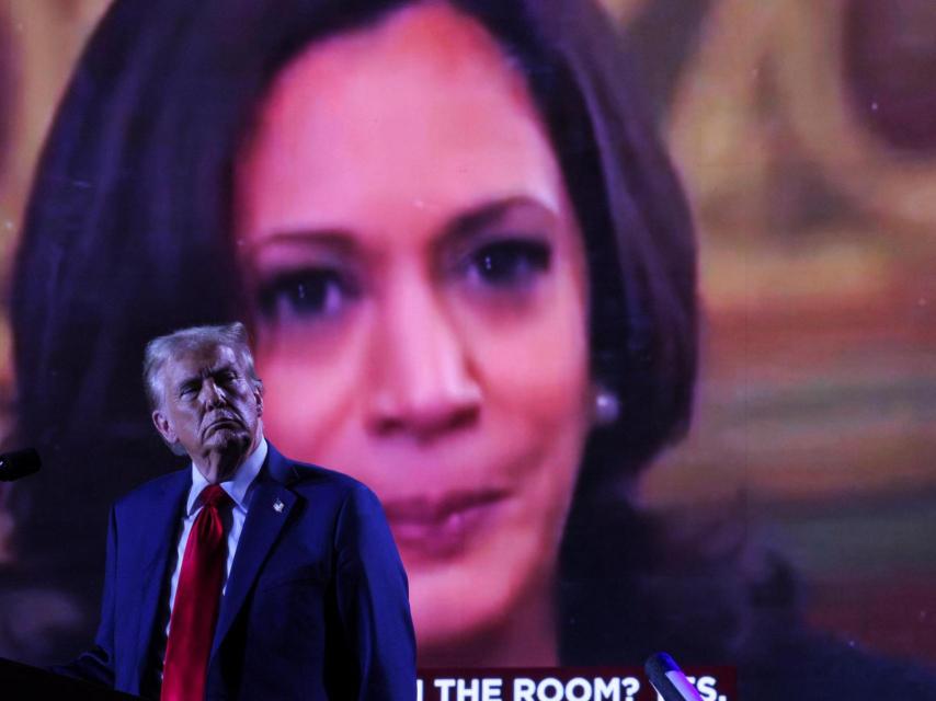 El candidato republicano Donald Trump frente a una pantalla donde se proyecta una imagen de su oponente, Kamala Harris, durante un mitin en Huntington Place.