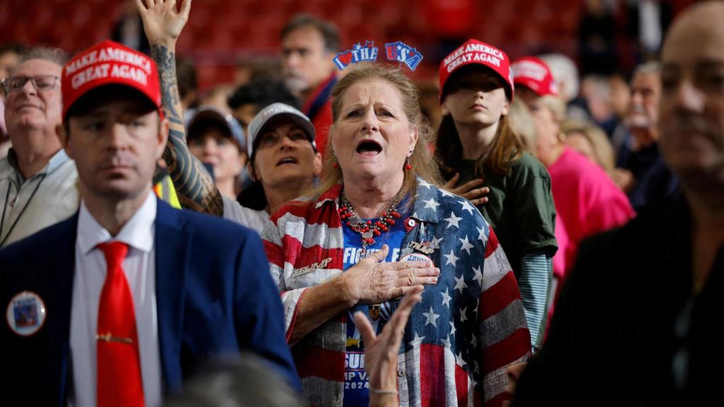 Un puñado de partidarios trumpistas cantan el himno nacional antes de un mitin en Carolina del Norte.