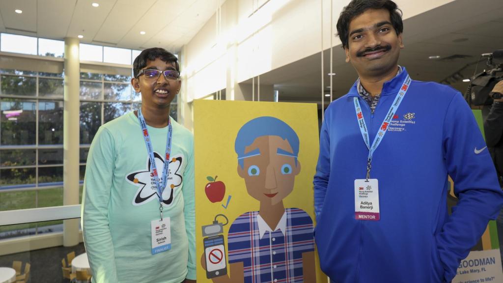 Sirish Subash y su mentor Aditya Banerji junto con cartel que muestra su dispositivo.