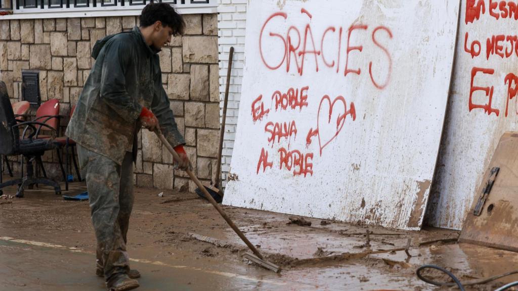 Una persona limpia las calles del municipio valenciano de Sedaví este martes, tras el paso de la DANA. Efe / Biel Alino