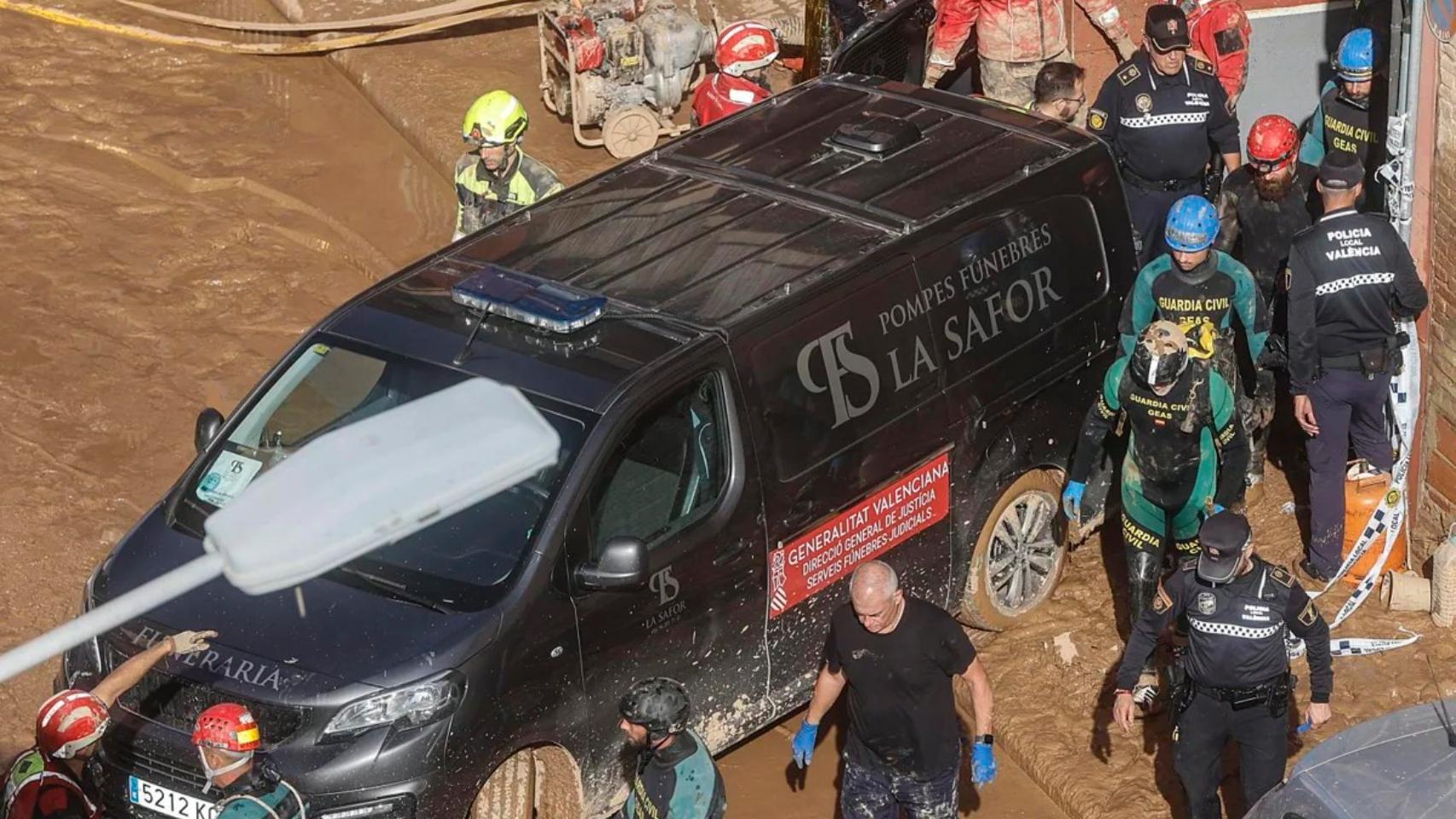 Un furgón de la funeraria sale de un garaje con cadáveres localizados tras el paso de la DANA en el barrio de la Torre, en Valencia.