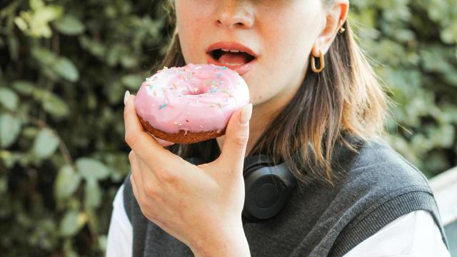 Mujer con gorra comiendo un donut