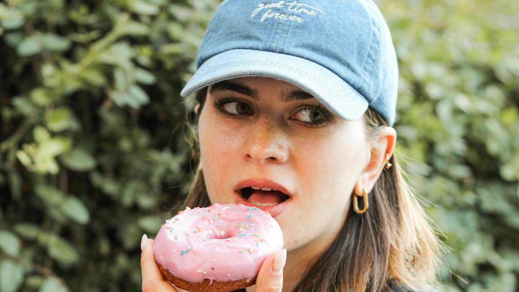 Mujer con gorra comiendo un donut