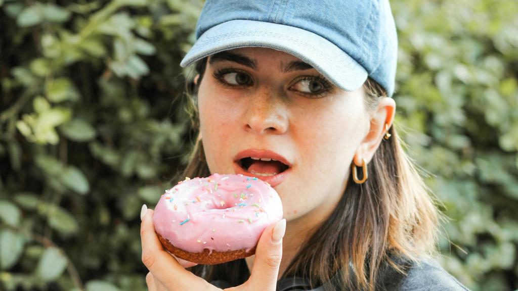 Mujer con gorra comiendo un donut