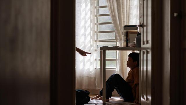 Imagen de un niño refugiándose debajo de una mesa por enfado de sus padres.