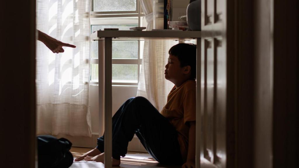 Imagen de un niño refugiándose debajo de una mesa por enfado de sus padres.