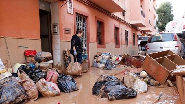 Una mujer saca de su vivienda sus pertenencias por la fuerte DANA en Catarroja