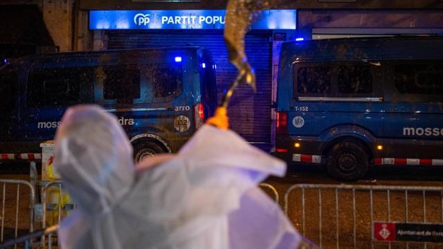 Un manifestante lanza barro hacia la sede del PP en Barcelona, este jueves,  en una protesta contra Carlos Mazón por la DANA.