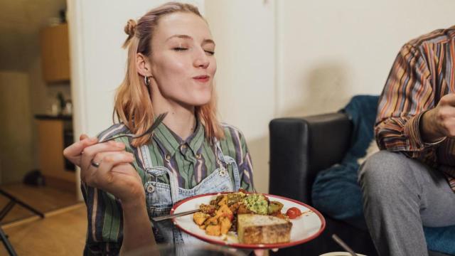 Mujer saboreando un plato de comida.