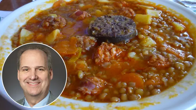 El doctor James Cox, junto a un plato de lentejas con chorizo y morcilla.