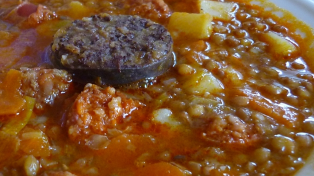 El doctor James Cox, junto a un plato de lentejas con chorizo y morcilla.