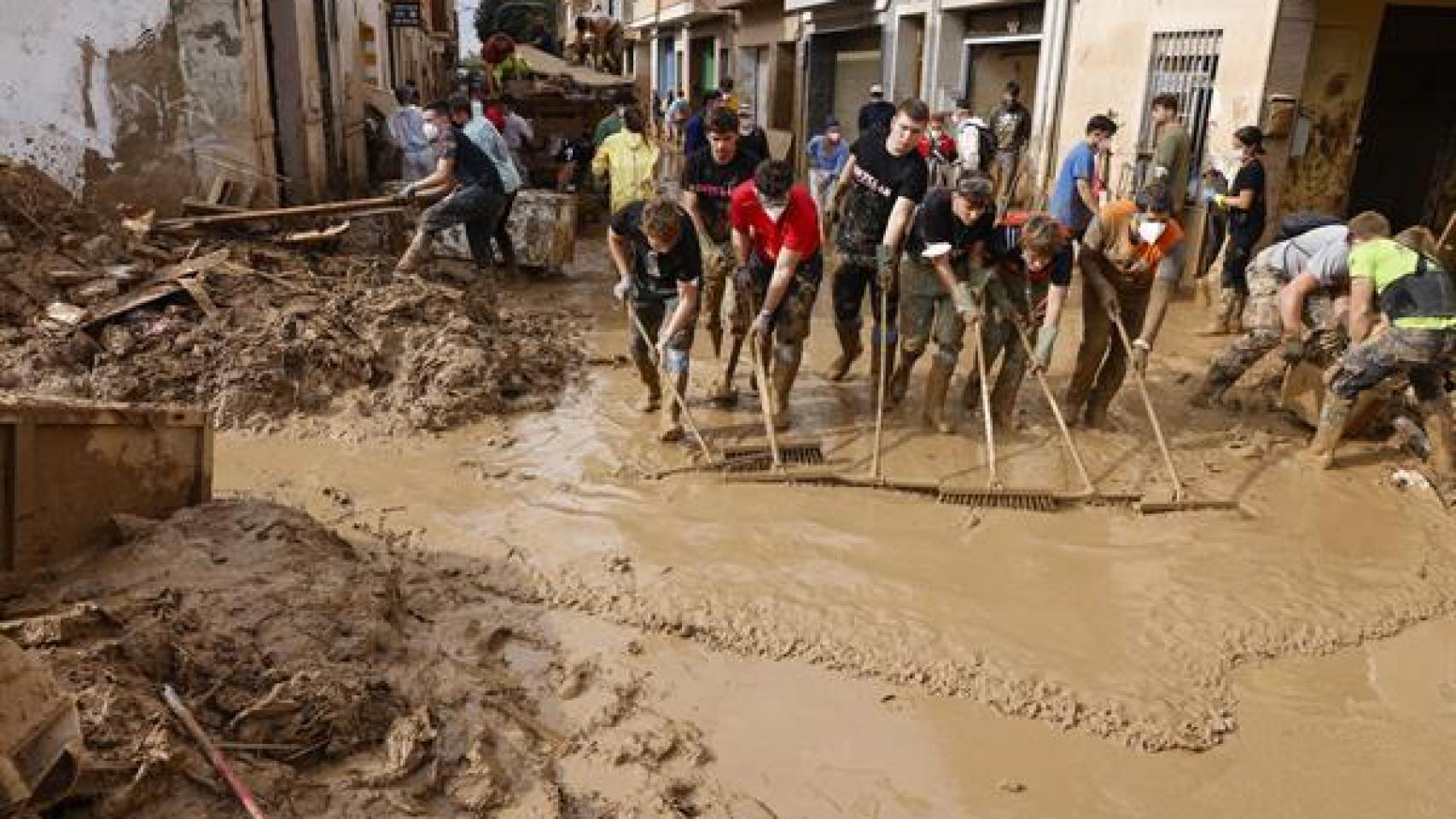 Voluntarios barren el lodo de una calle de Masanasa (Valencia).