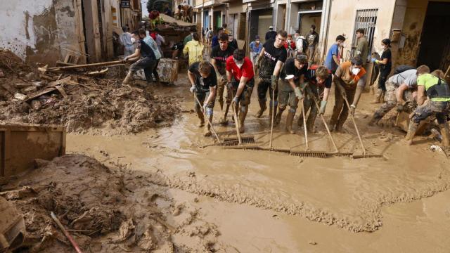 Voluntarios barren el lodo de una calle de Masanasa (Valencia) este jueves