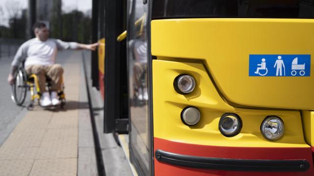 Persona en sillas de ruedas intentando subir a un autobús.