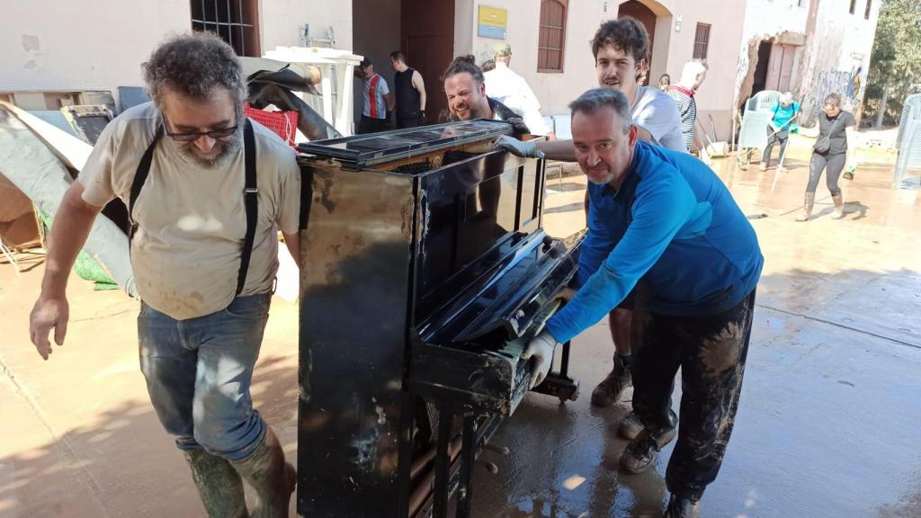 Miembros del colectivo Sedajazz trasladan un piano después de que su sede, oficinas y su escuela quedasen anegadas bajo el agua y el fango. Efe / Sedajazz