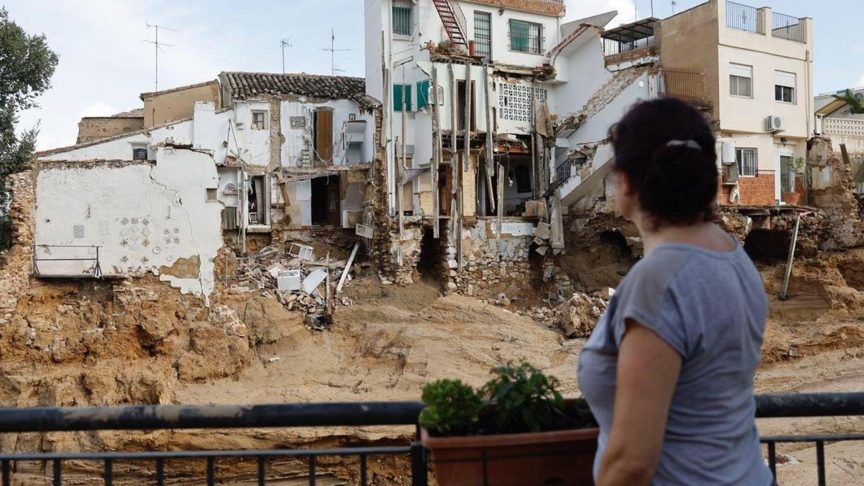 Una mujer observa su casa derruida.