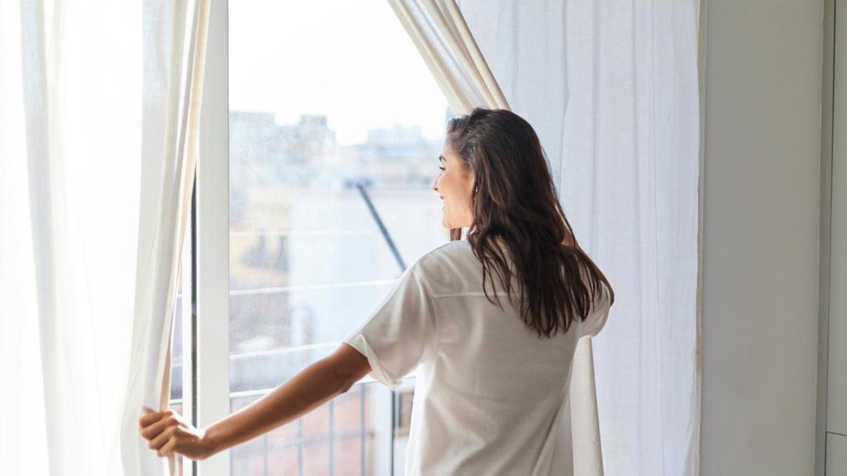 Mujer abriendo unas cortinas.