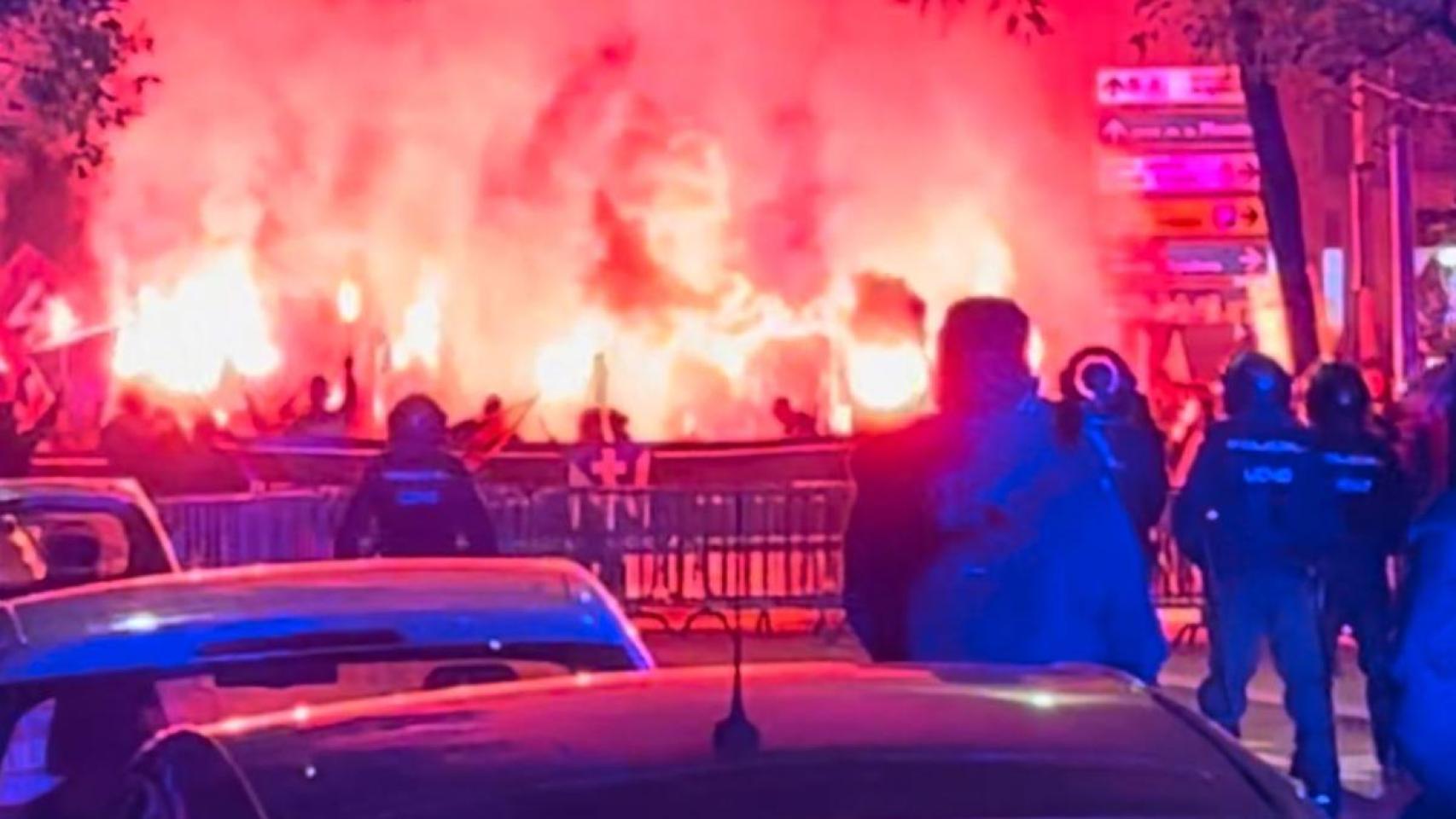 Manifestantes con bengalas tras la barrera de seguridad de Ferraz, el sábado por la noche, y bajo la mirada de la Policía Nacional.