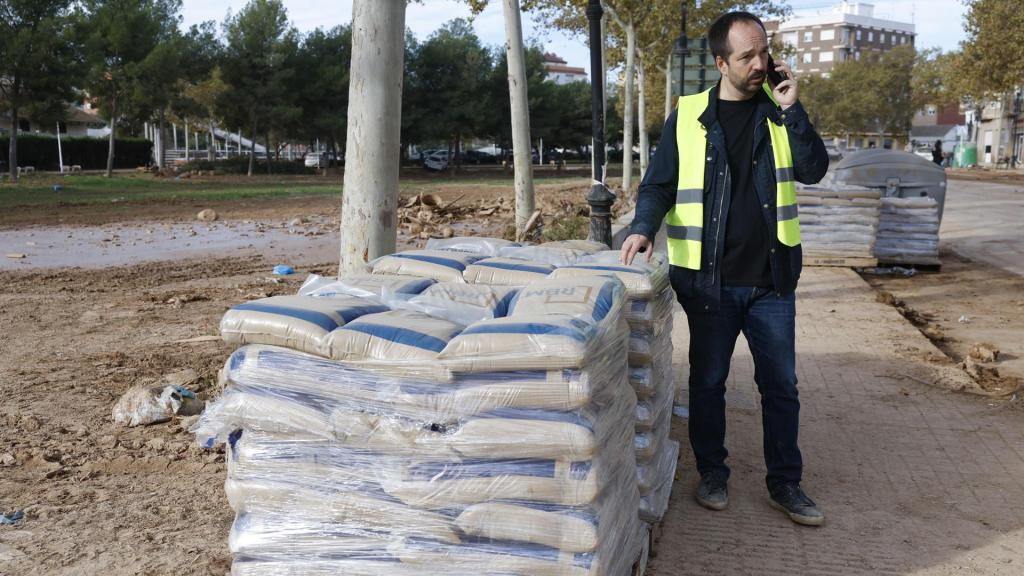 Guillermo Luján conversa con por teléfono junto a varios palés de arena