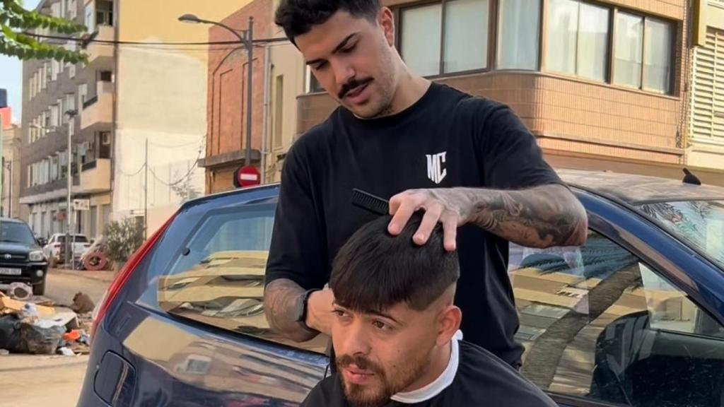 Marcos, el peluquero de Alfafar, corta el pelo a sus vecinos en la calle.