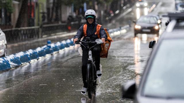 Un repartidor trabaja bajo la lluvia en Madrid.