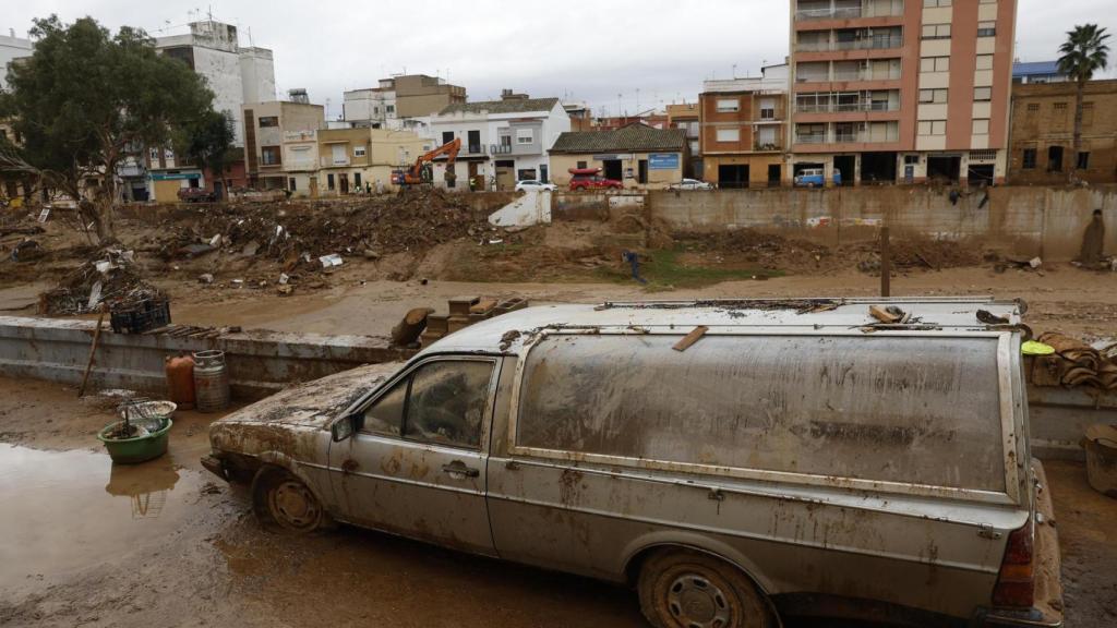 Un coche fúnebre semienterrado en lodo en una calle de Paiporta, este miércoles. paraguas en el interior de una casa en Paiporta (Valencia) este miércoles.