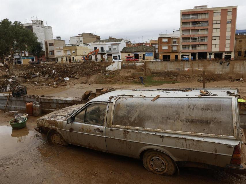 Un coche fúnebre semienterrado en lodo en una calle de Paiporta.