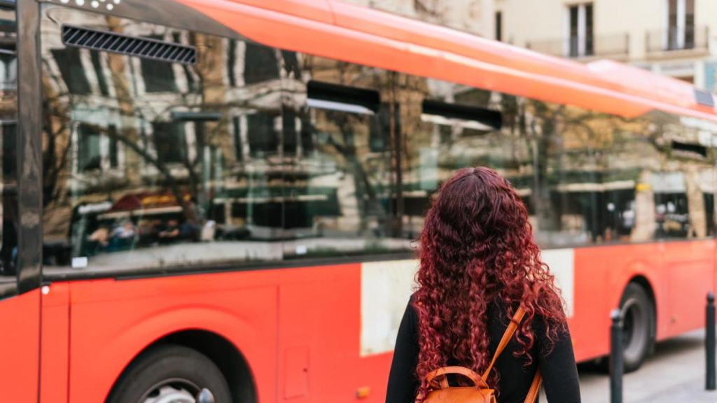 Mujer esperando en la parada de un autobús urbano.