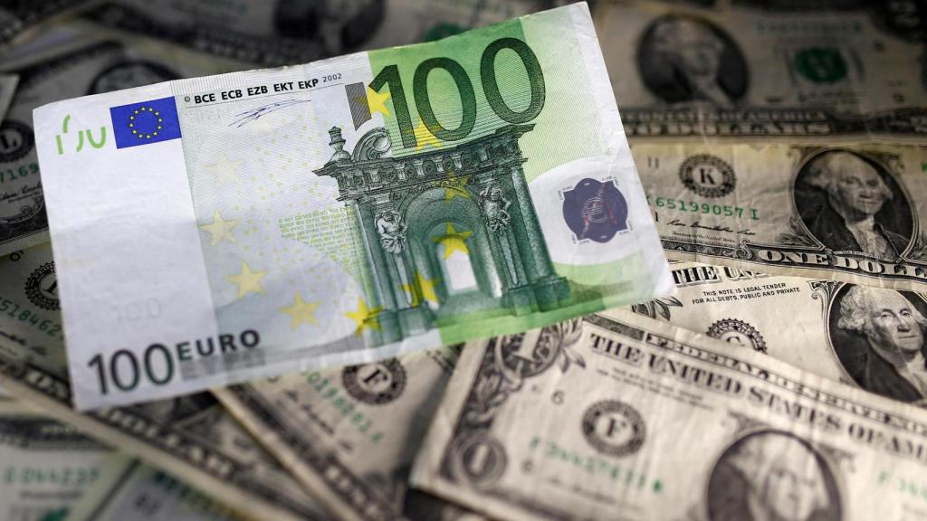 Un billete de 100 euros sobre varios billetes de un dólar.